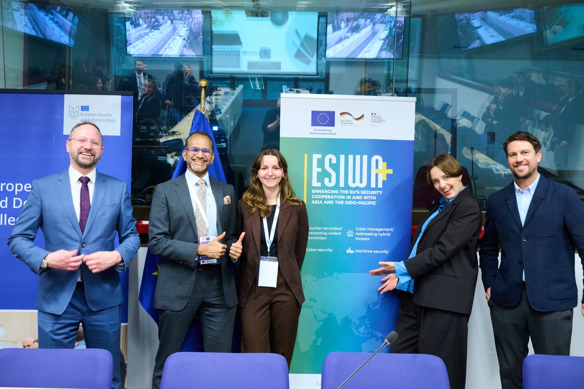 Five people standing together in front of an ESIWA+ banner in a conference room